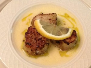 Seared sea scallops with a beurre blanc sauce and saffron oil, topped with lemon garnish